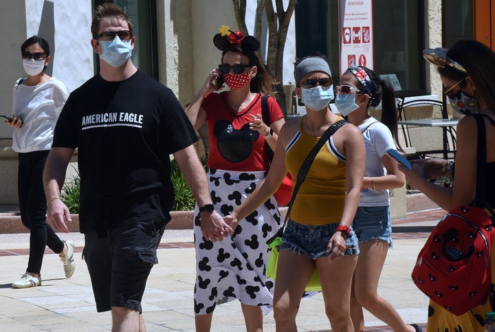 People flocked to Disney Springs ― the retail, dining and entertainment complex at Walt Disney World ― on the day it began its phased reopening in May. Masks and temperature checks are required there as well.