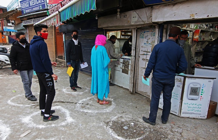 People maintain social distancing, due to the coronavirus (Covid-19) pandemic as they wait for their turn to collect medicines from a pharmacy in Srinagar, Kashmir, India on March 26, 2020.