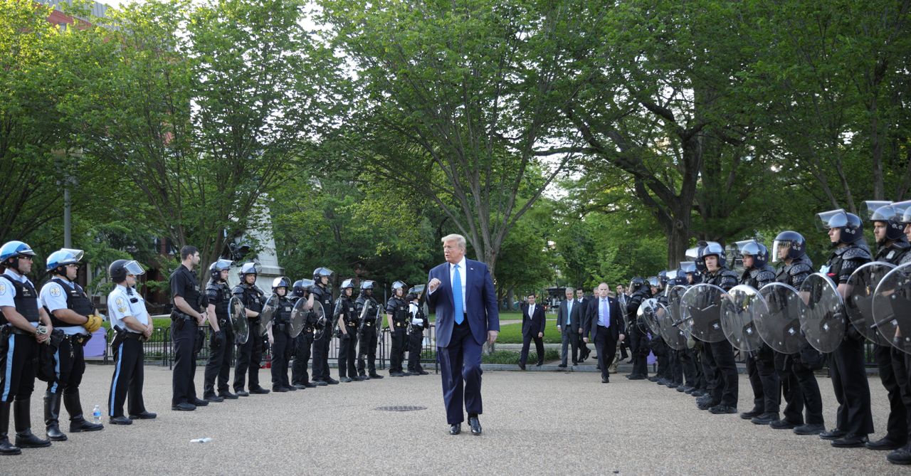 Trump walks between lines of riot police in Lafayette Park across from the White House while walking to St John's Church for a photo opportunity during ongoing protests over racial inequality.