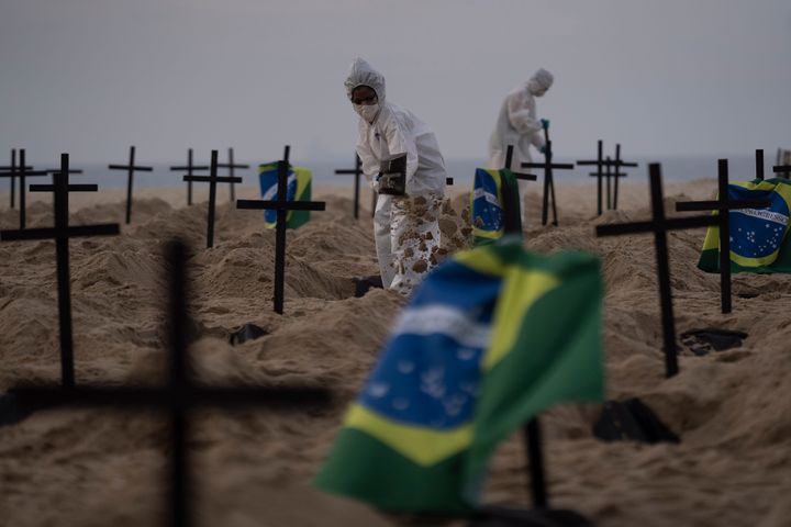 Activists in costume from the NGO Rio de Paz dig symbolic graves on Copacabana beach to protest the government's handling of the Covis-19 pandemic in Rio de Janeiro.