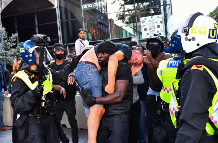 A protester carries an injured counter-protester to safety, near the Waterloo station during a Black Lives Matter protest fol