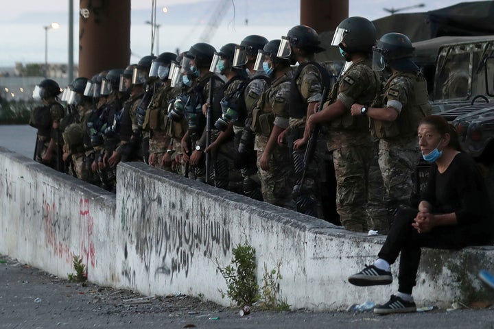 An anti-government protester, right, sits near Lebanese army soldiers standing guard in Beirut, Lebanon, Saturday, June 13, 2020. (AP Photo/Hassan Ammar)