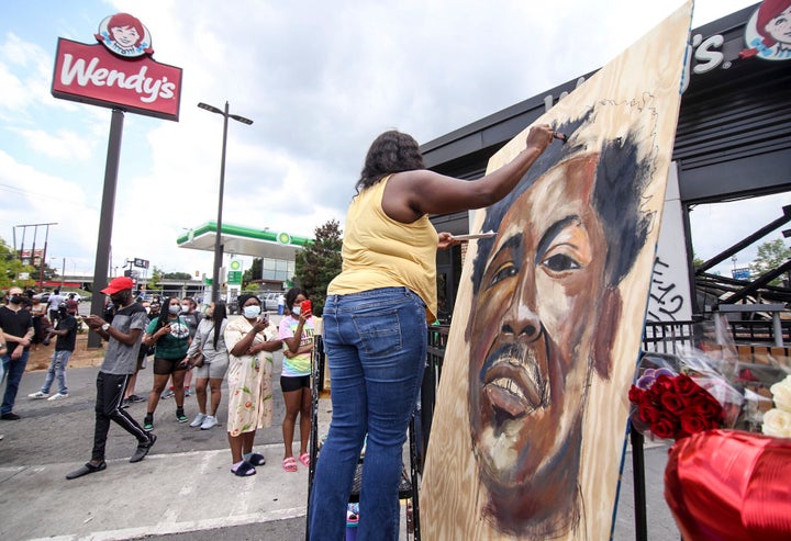 Ashley Dopson paints a picture of Rayshard Brooks in the parking lot of the Wendy's in Atlanta where Brooks, a 27-year-old black man, was shot and killed by Atlanta police Friday evening during a struggle in the Wendy's drive-thru line. (Steve Schaefer/Atlanta Journal-Constitution via AP)