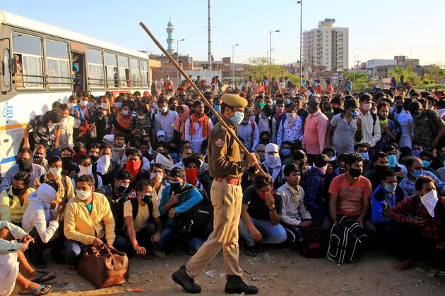 Security personnel with migrants who are waiting to board a bus to their native places in Jaipur, Rajasthan,...