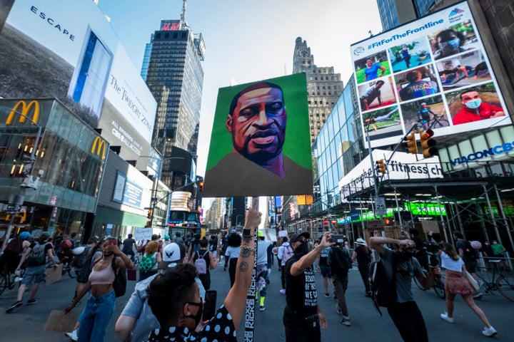 People protesting police brutality walk through Times Square with a portrait of George Floyd. 