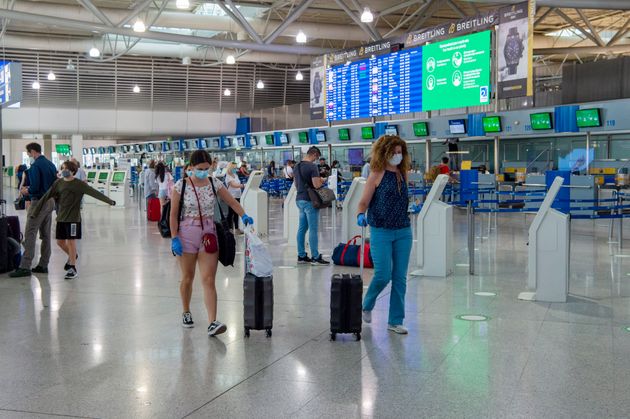 Επιβάτες φορούν προστατευτικές μάσκες και γάντια καθώς φτάνουν στο αεροδρόμιο Ελευθέριος Βενιζέλος. 