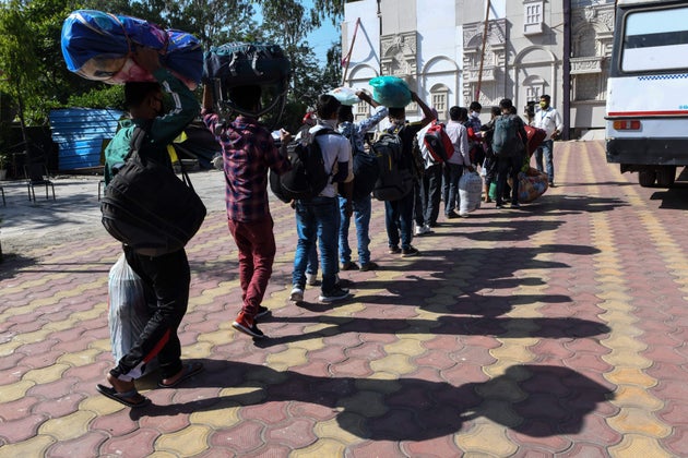 Migrant workers and their families line up to board a bus to Amritsar railway station to take a...