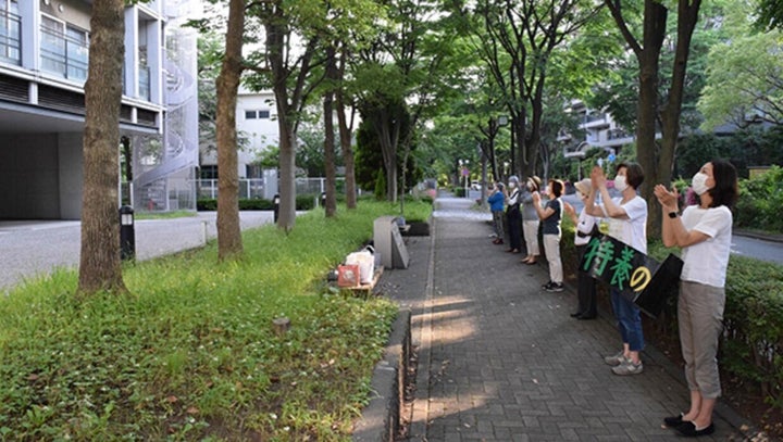 施設（左側）に拍手を送る地域住民ら（５月２７日）