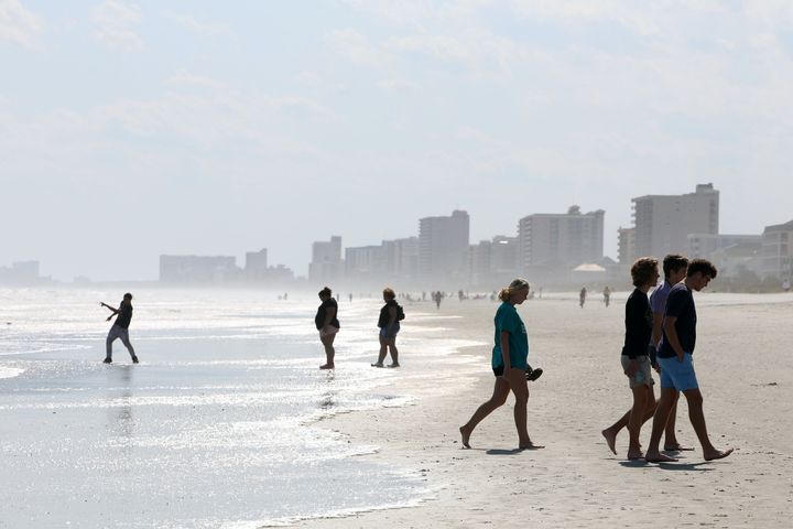 People walk along the shore as beaches reopen after closures aimed at preventing the spread of coronavirus disease (COVID-19) in North Myrtle Beach, South Carolina, U.S., April 21, 2020. (REUTERS/Rachel Jessen)