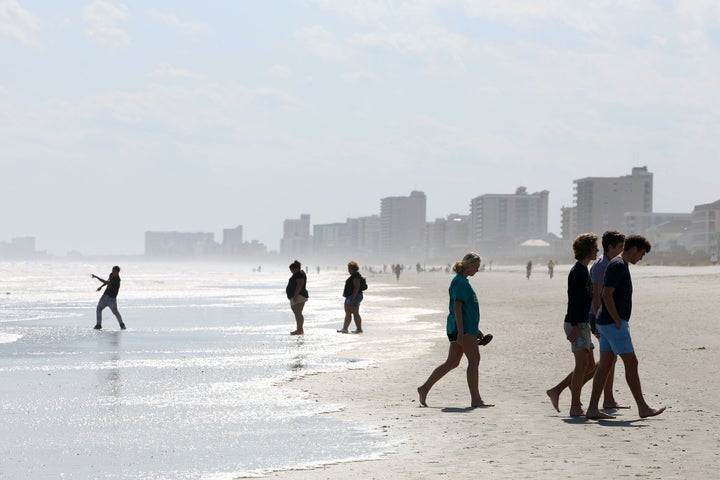 People walk along the shore as beaches reopen after closures aimed at preventing the spread of coronavirus disease (COVID-19)