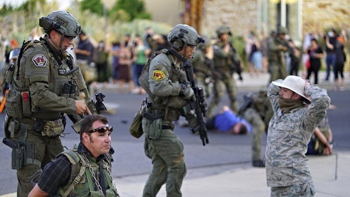 Albuquerque police detain members of the New Mexico Civil Guard, an armed civilian group, following the shooting of a man during a protest over a statue of Spanish colonial official Juan de Oñate on Monday.