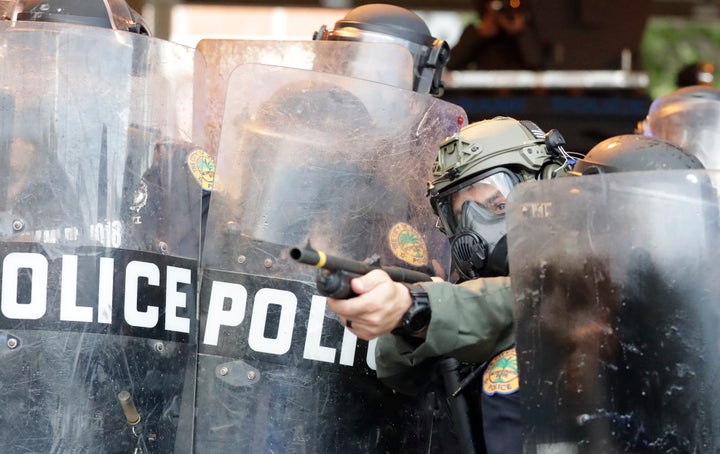 A policeman shoots rubber bullets at protesters throwing rocks and water bottles during a demonstration next to the city of Miami Police Department on May 30 in Miami.