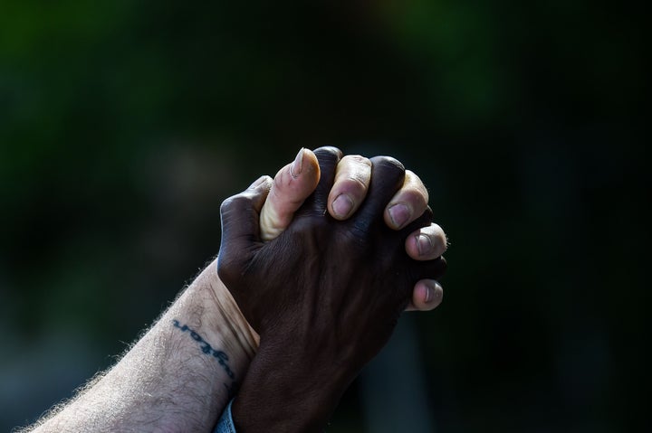 Men hold hands as they protest Rayshard Brooks' shooting death by police in a Wendy's restaurant parking lot on June 16, 2020, in Atlanta.