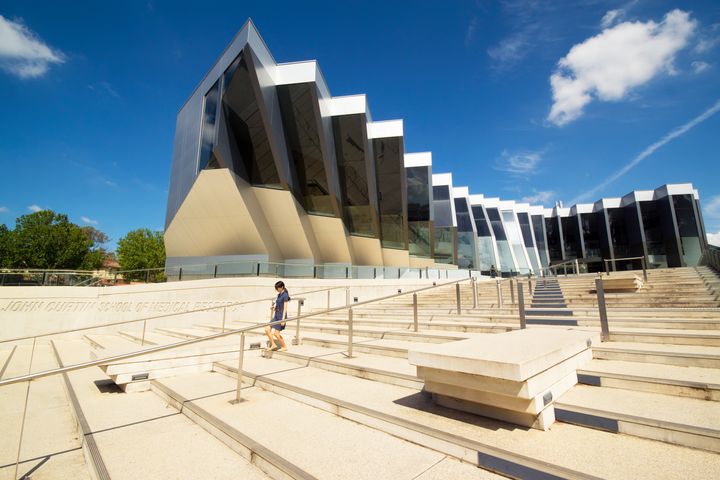 A woman walks down steps before the John Curtin School of Medical Research at the Australian National University.