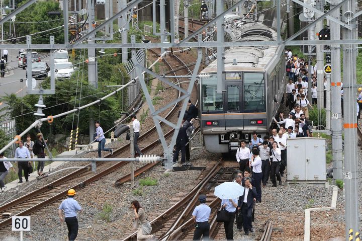 線路の横を歩いてJR新大阪駅に向かう乗客＝2018年6月18日、大阪市淀川区