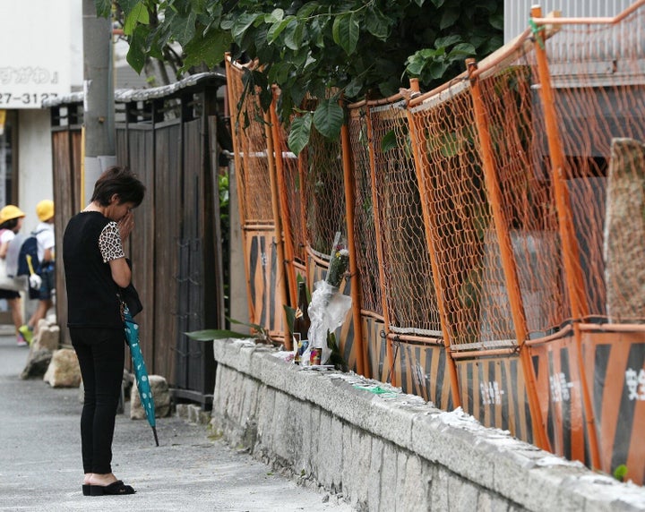 民家の外壁の下敷きとなった男性が死亡した現場で手を合わせる女性＝2018年6月19日、大阪市東淀川区