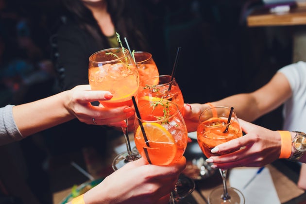 women raising a glasses of Spritz at the dinner table
