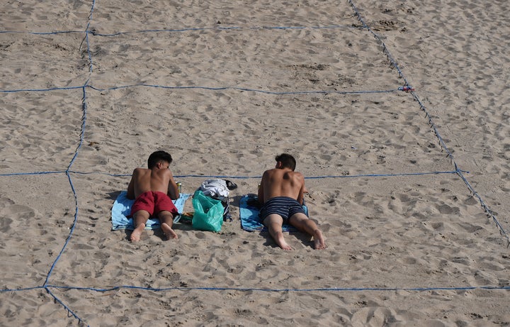 Two men sunbathe in their designated roped-off area on Poniente Beach in Benidorm, Spain, on June 16.