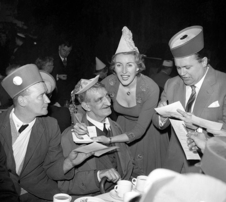 Dame Vera Lynn and comedian Harry Secombe (right) signing autographs at the tea tables during the Not Forgotten Association annual Christmas party in 1956