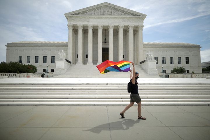Joseph Fons, holding a Pride flag, walks in front of the U.S. Supreme Court building after the court ruled that LGBTQ people can not be disciplined or fired based on their sexual orientation on June 15, 2020, in Washington, D.C.