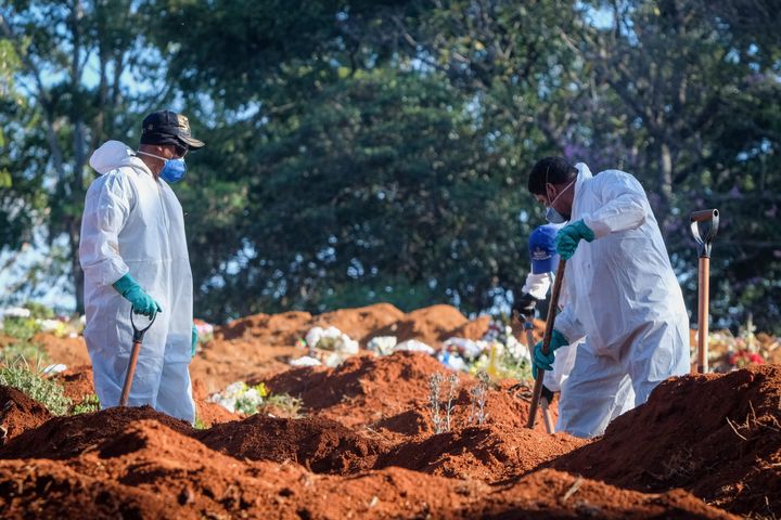 Cemetery workers in protective suits shovel earth at the Vila Formosa cemetery in the Brazilian city of Sao Paulo amid the co