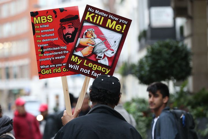 A man holds posters denouncing Saudi Crown Prince Mohammed bin Salman and hailing killed journalist Jamal Khashoggi during a protest outside the Saudi Arabian embassy in central London.