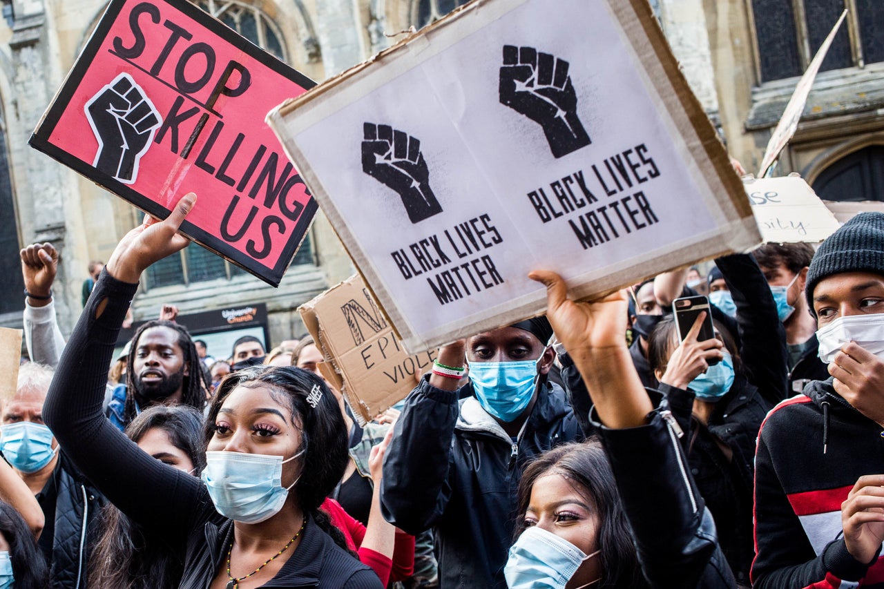 Protesters wearing face masks and holding placards during a protest outside the University of Oxford's Oriel College. The statue of British imperialist Cecil Rhodes above one of its entrances will be removed, the college's governors have since confirmed