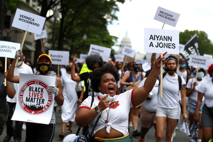Juneteenth demonstrators march down Pennsylvania Avenue while holding signs bearing the names of Black transgender women killed by police.