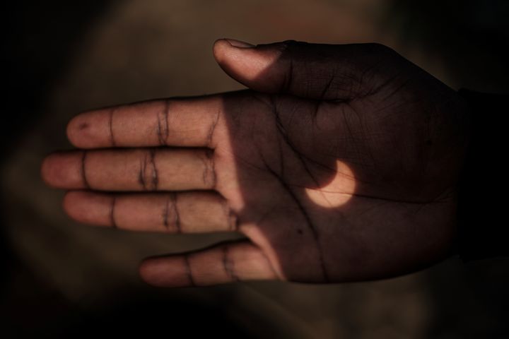 The partial solar eclipse is projected on a Kenyan man's hand through binoculars in Nairobi, Kenya on June 21, 2020. 