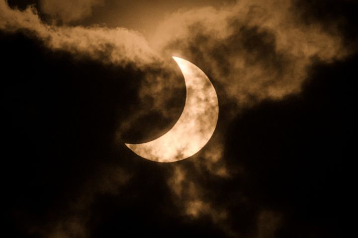 The partial solar eclipse is captured using infra red filter in the cloudy sky in Nairobi, Kenya on June 21, 2020. 