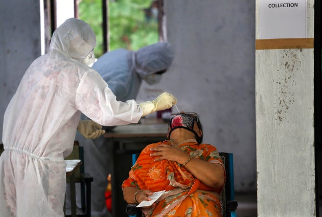 A health worker takes a nasal sample of a woman for the COVID-19 rapid antigen test in New Delhi, June...
