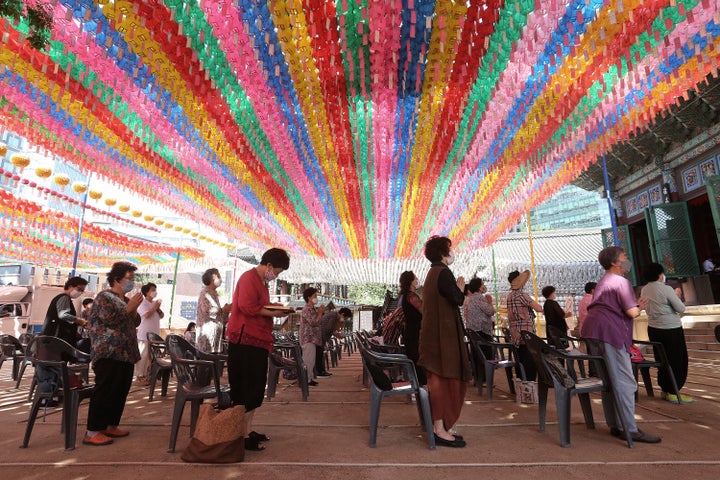 People wearing face masks to help protect against the spread of the new coronavirus pray while maintaining social distancing during a service at the Chogyesa temple in South Korea on June 22, 2020. 