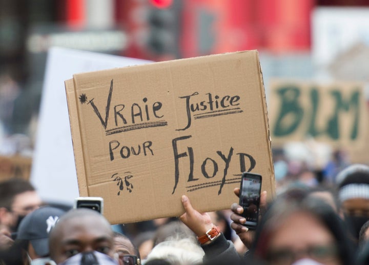 Des gens brandissent des pancartes lors d'une manifestation à Montréal réclamant justice pour la mort de George Floyd et de toutes les victimes de la brutalité policière le 31 mai dernier. 