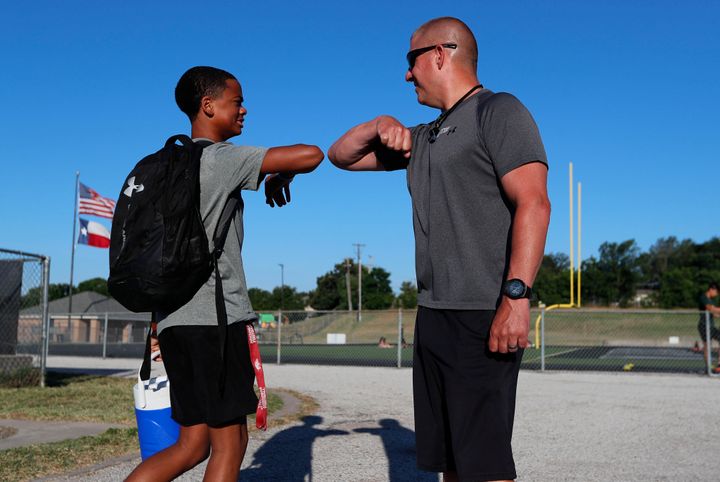 Head football coach Bob Wager, right, and sophomore safety Cameron Conley greet each other at the re-opening of strength and conditioning camp at Arlington Martin High School, Thursday, June 18, 2020, in in Arlington, Texas. While states have been easing the economic and social lockdowns prompted by the coronavirus pandemic, some are now letting high school athletes return for summer workouts before teachers have even figured out how they are going to hold classroom instruction. (AP Photo/LM Otero)