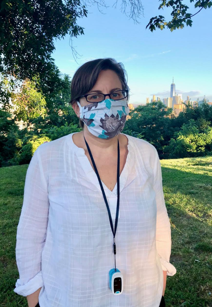 The author, masked and with her oximeter around her neck, on a walk in her Jersey City neighborhood with the Freedom Tower in the background in June 2020.