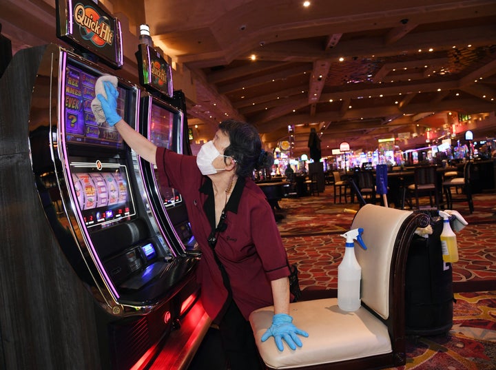 An employee sanitizes slot machines at Excalibur Hotel & Casino after the property opened for the first time since mid-Ma