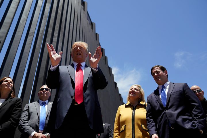 President Donald Trump tours a section of the border wall on Tuesday in San Luis, Arizona, accompanied by Arizona Gov. Doug Ducey (R), second from right, and Rep. Debbie Lesko (R-Ariz), third from right.