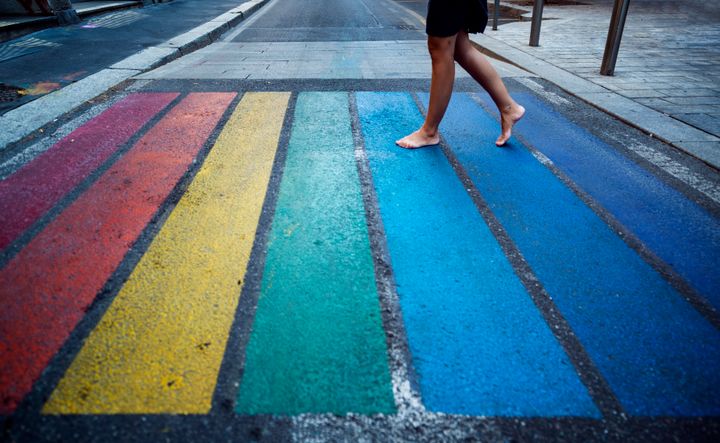Milan, Italy. A woman walks barefoot over a pedestrian crossing in rainbow colors.