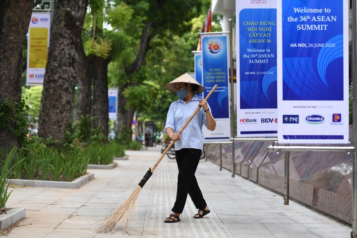 A woman sweeps the street next to banners for the 36th ASEAN Summit by the International Convention Cente in Hanoi on June 25, 2020, a day before the summit is set to be held online due to the COVID-19 coronavirus pandemic. (Photo by Nhac NGUYEN / AFP) (Photo by NHAC NGUYEN/AFP via Getty Images)