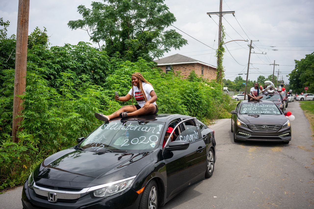 Trevianne Turner rides on top of her sister's car during a Dr. Martin Luther King Jr. High School graduation parade through the Lower 9th Ward in New Orleans on May 20.
