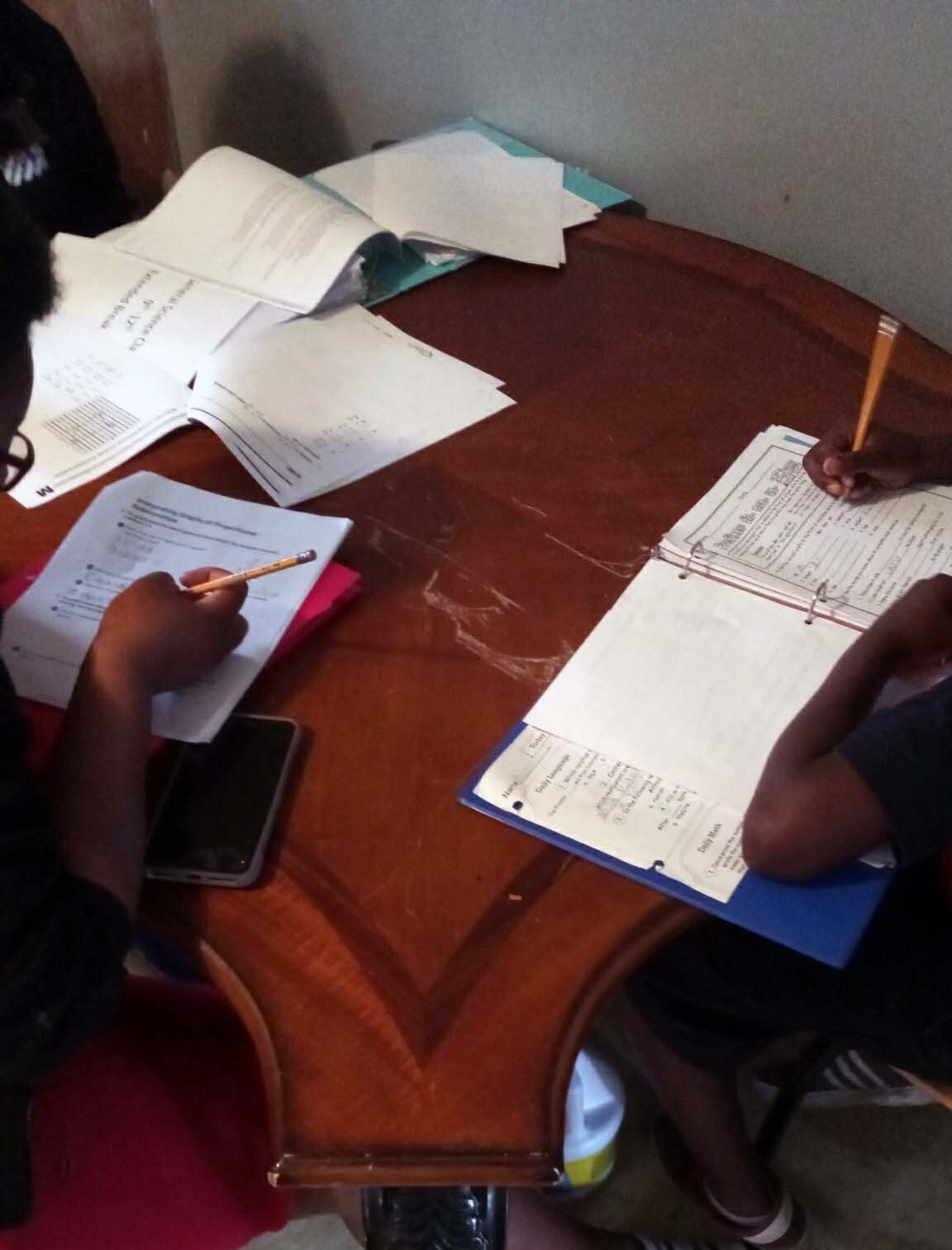 Amareon, right, and his sister Jakayla work on assignments picked up from their local school district. Their family does not have a computer or broadband Internet at home, so the siblings have to take turns sharing their mom’s phone to access online lessons.