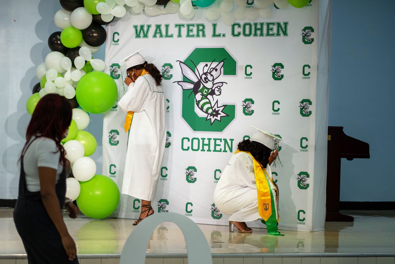 Jade Brown, left and Satoriya Lambert break down in tears as they sing their school song at Walter L. Cohen College Prep. Because of pandemic restrictions, she was allowed to bring only three family members for her 15-minute graduation ceremony.