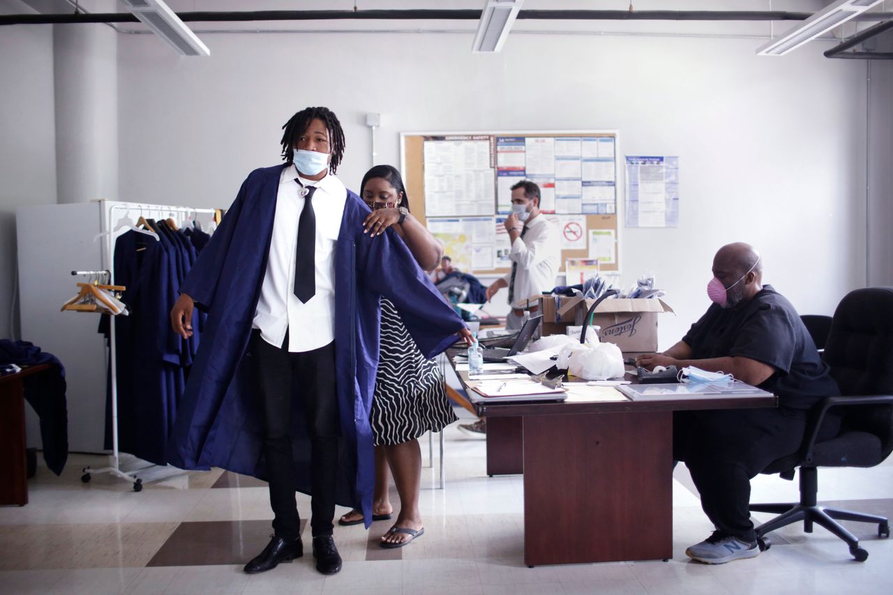 Jarrin Rainey gets help with his gown from school staffer Danneka Mitchell just before his graduation ceremony at Frederick A. Douglass High School in late May.