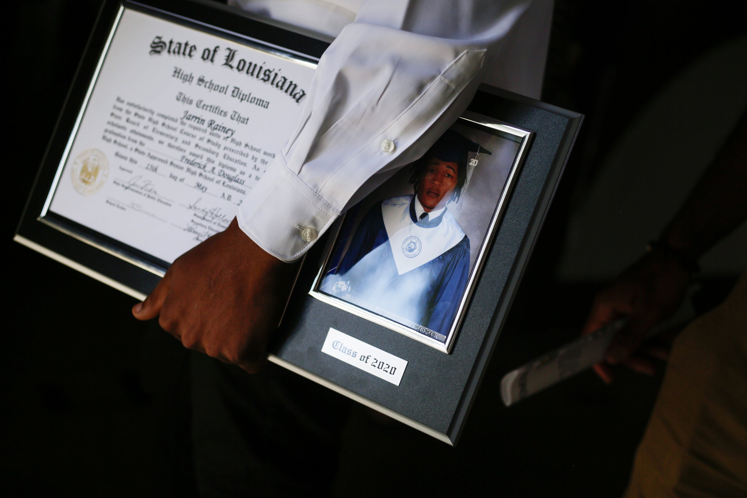 Jarrin Rainey holds his diploma and senior picture plaque after his graduation ceremony at Frederick Douglass High School in