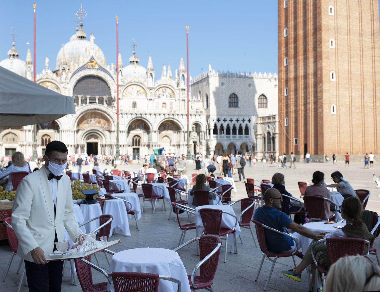 Waiters wearing protective face masks work on the patio facing the Piazza San Marco in Venice, Italy, on June 13.