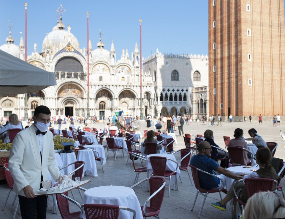 Waiters wearing protective face masks work on the patio facing the Piazza San Marco in Venice, Italy, on June 13.