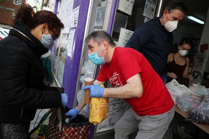 Una mujer recibe comida de unos voluntarios de la asociación de vecinos Parque Aluche, en Madrid, durante la cuarentena. 