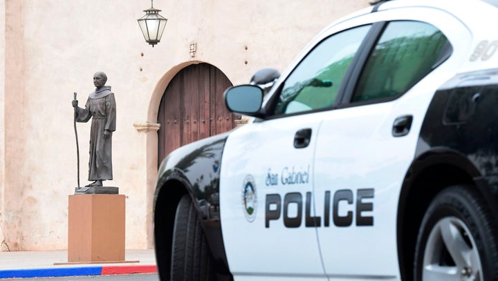 A police vehicle parks near a statue of Junipero Serra in front of the San Gabriel Mission in San Gabriel, California, on Sunday.