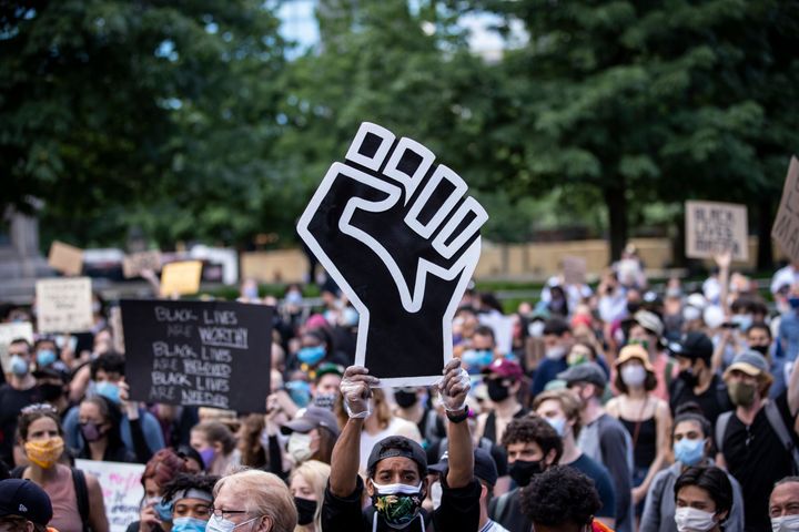 A protester wearing a mask holds a large Black power raised fist in the middle of a crowd that gathered at Columbus Circle on June 14, 2020, in New York City.