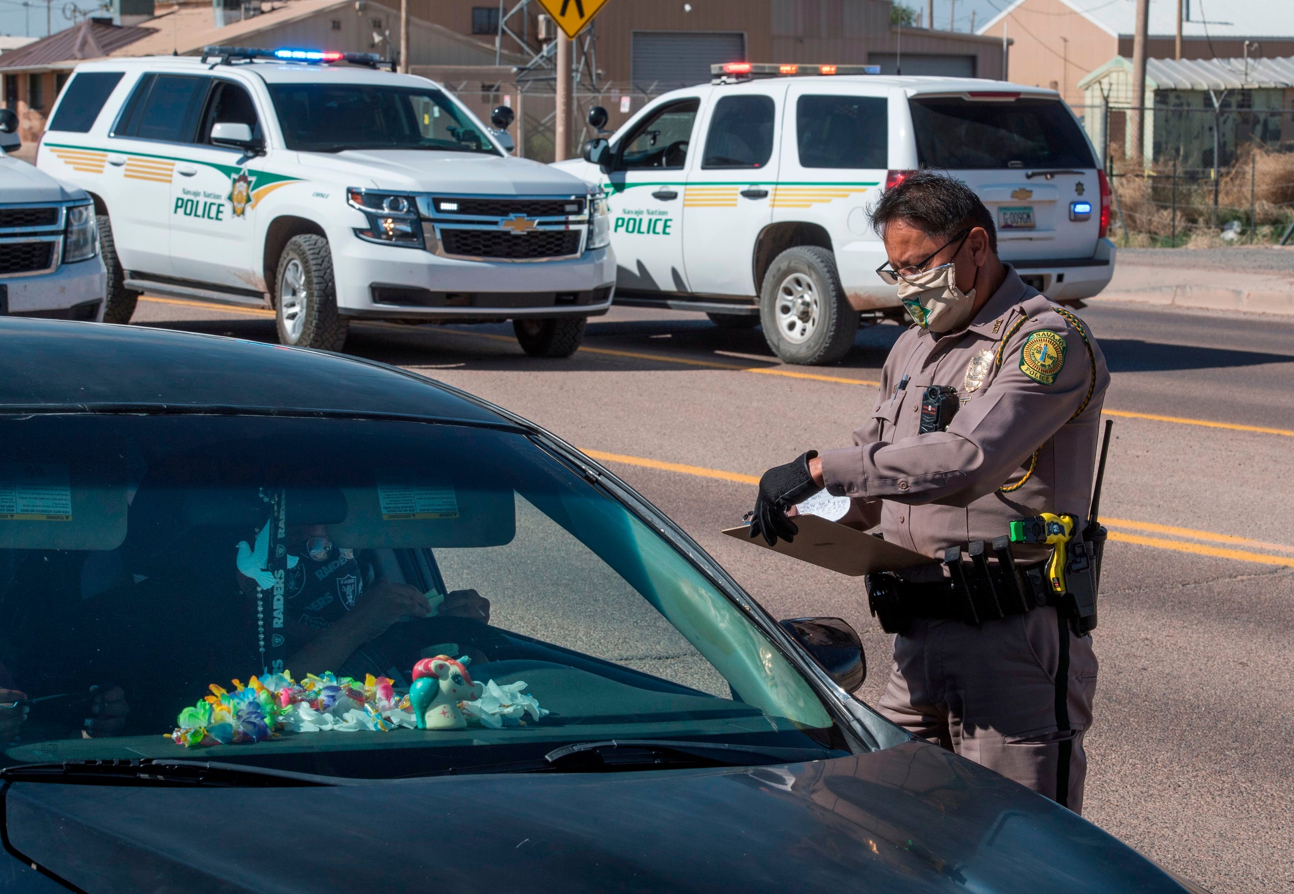 A Navajo Nation police officer issues a fine to a driver who ignored the 57-hour curfew imposed to try to stop the spread of